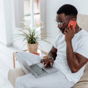 Man on phone using laptop. Online bookkeeping, national certificate in commerce.